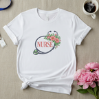 White floral tee on linen with flowers, badge, coffee